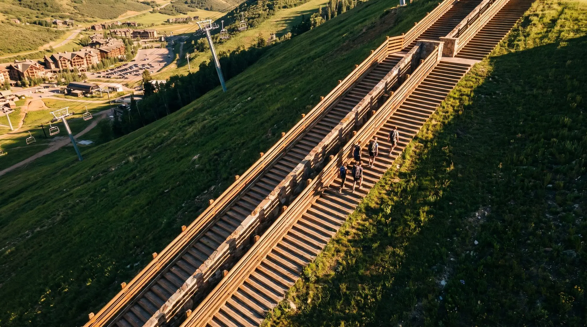 Concept render: a two-lane public staircase climbing a green ski slope above Park City Mountain Village at golden hour